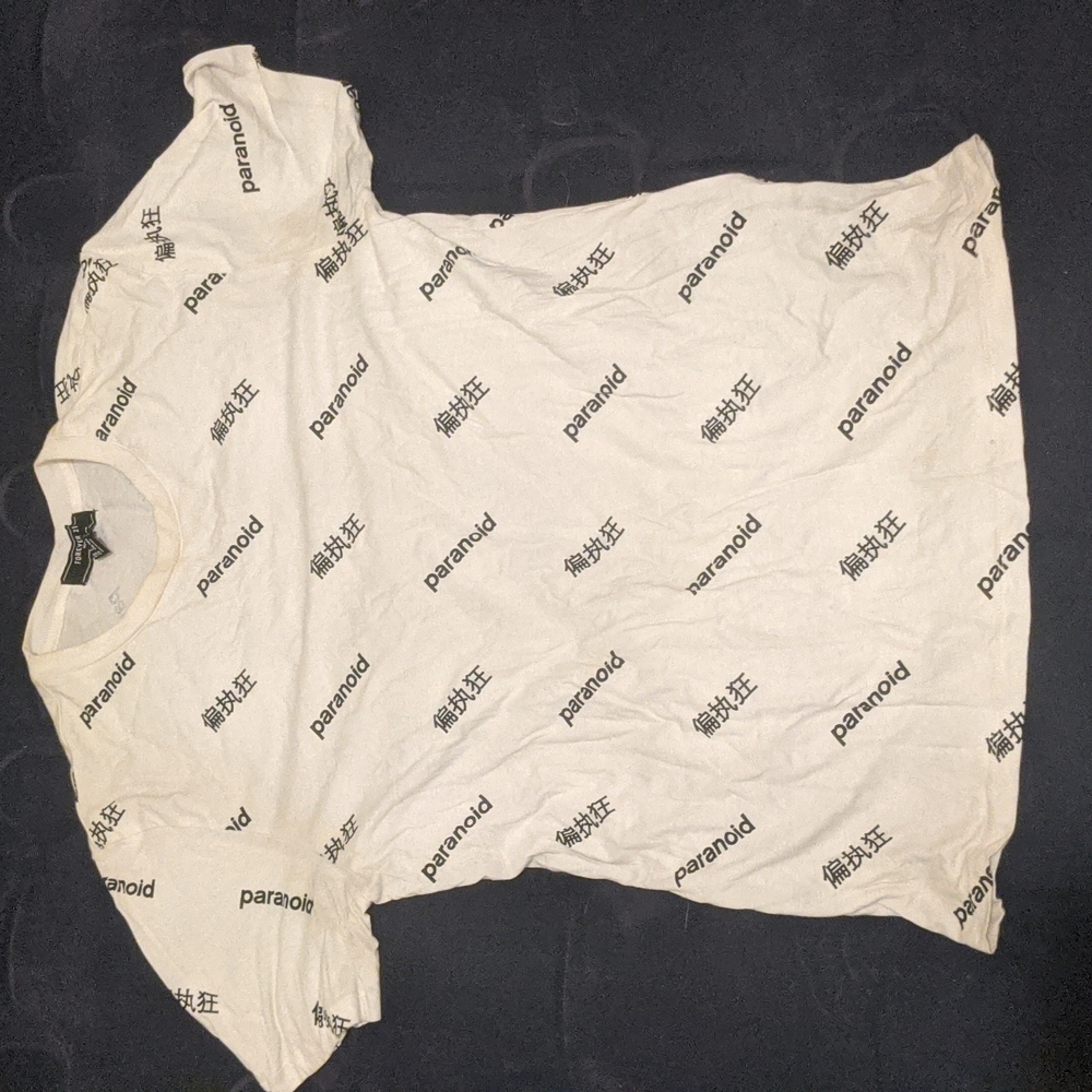 White "paranoid" shirt sleeve shirt with foreign lettering in black.